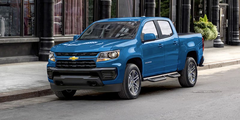 Image of a Blue 2022 Chevrolet Colorado pickup truck parked on a city street in front of a modern black building