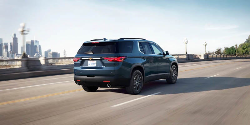 Image of a dark blue color 2023 Chevrolet Traverse driving on the bridge