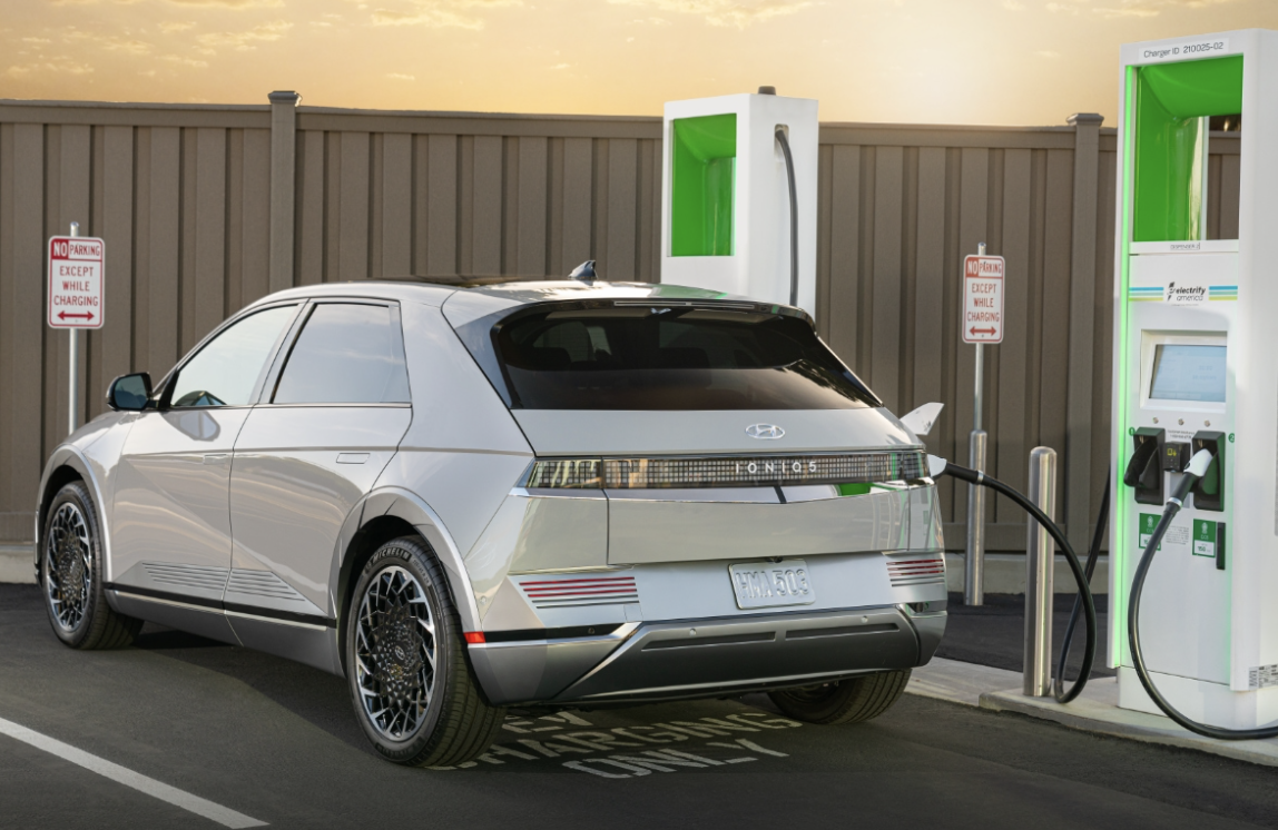 Image of silver Hyundai Ioniq 5 is parked in the parking lot and connected to the charging station.